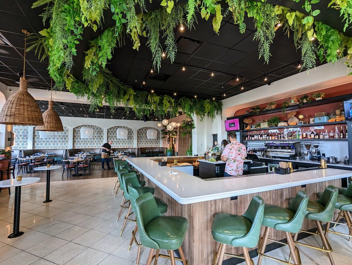 Image is inside Amador with a bar to the right, tables and both center and greenery flowing from the ceiling.