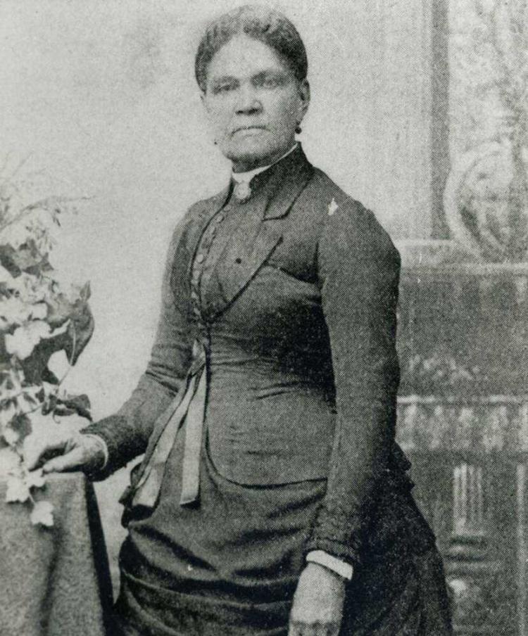 An antique photograph shows a women looking sternly at the camera.