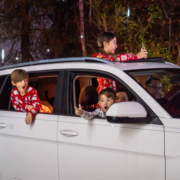 Kids leaning out of a car looking at holiday lights