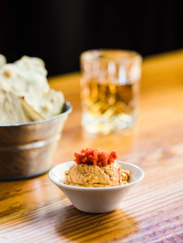 Cup of pimento cheese dip with chips and glass of bourbon