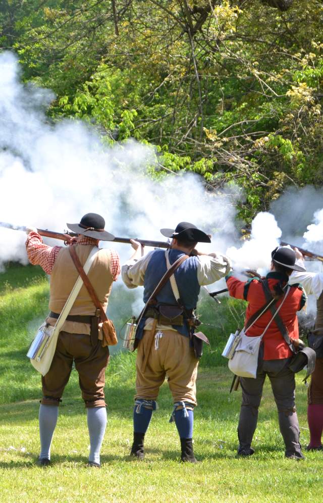 Revolutionary War reenactment. Line of men shooting muskets
