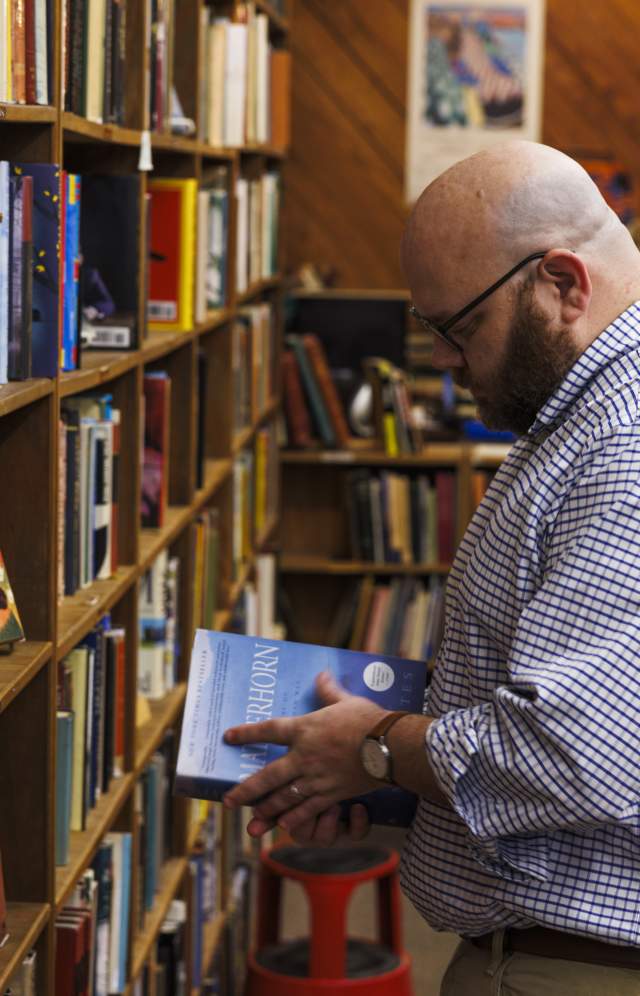 Man selecting a book from a shelf in a cozy used bookstore