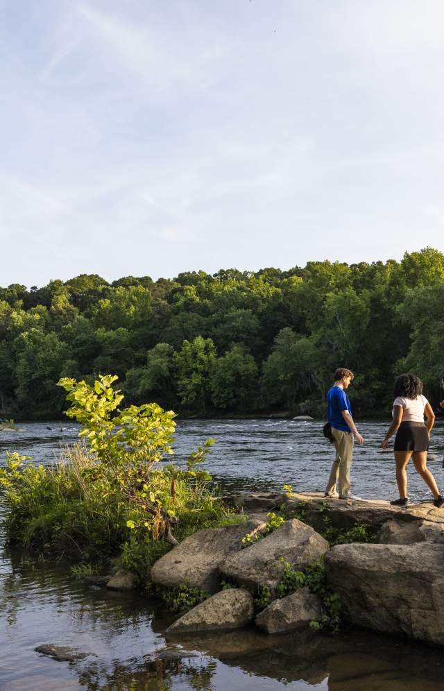 4 people standing next to a river