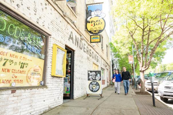 Couple walking down a street next to a record shop