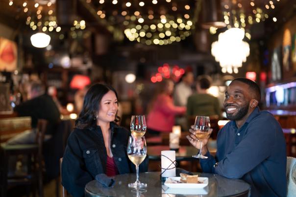 Couple sitting under twinkly lights, drinking wine