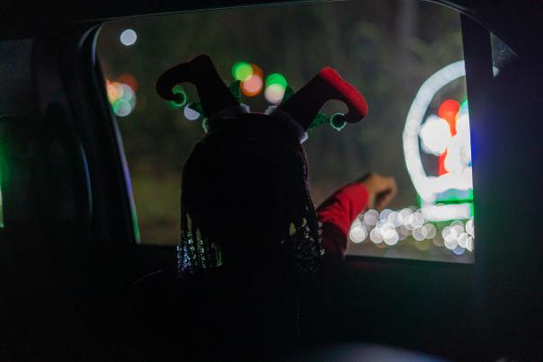 Child pointing out of a car window at holiday lights