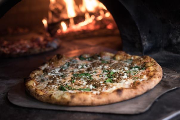 Pizza coming out of wood fire oven