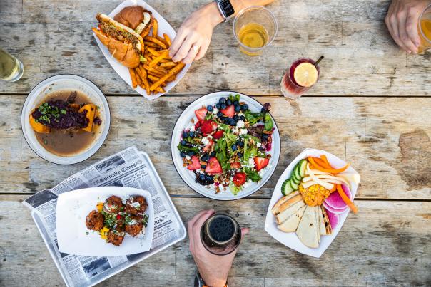 Lunch items displayed in a flat lay style with hands reaching in for drinks and food.