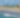 Aerial view of a sandy beach with ocean waves meeting the shoreline.
