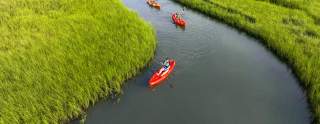 three people kayaking in the marsh