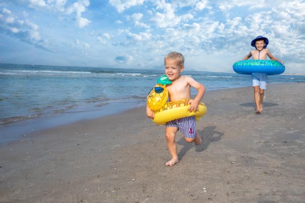 young kids running on beach wearing tubes