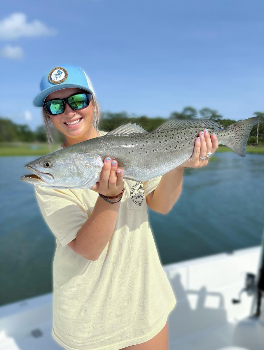 person holding a trout on a sunny day