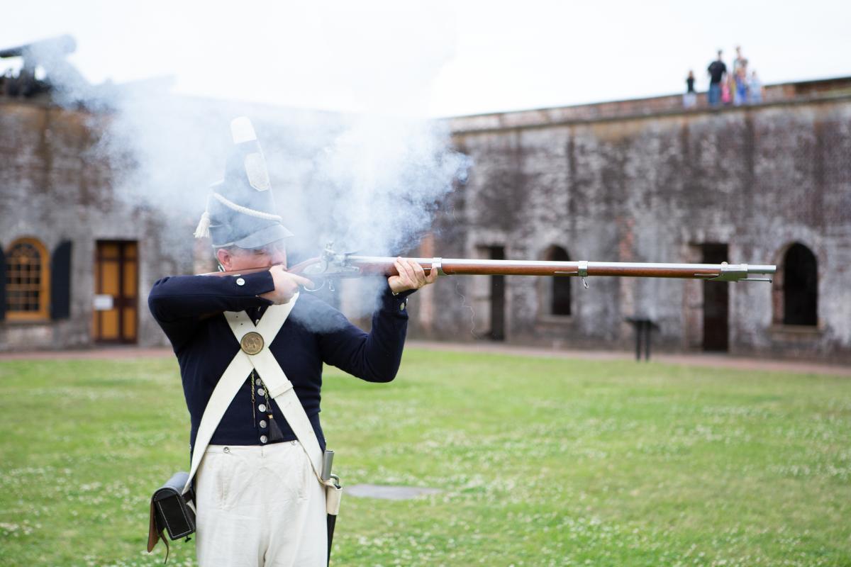 Park Ranger in old military uniform fire historic gun.
