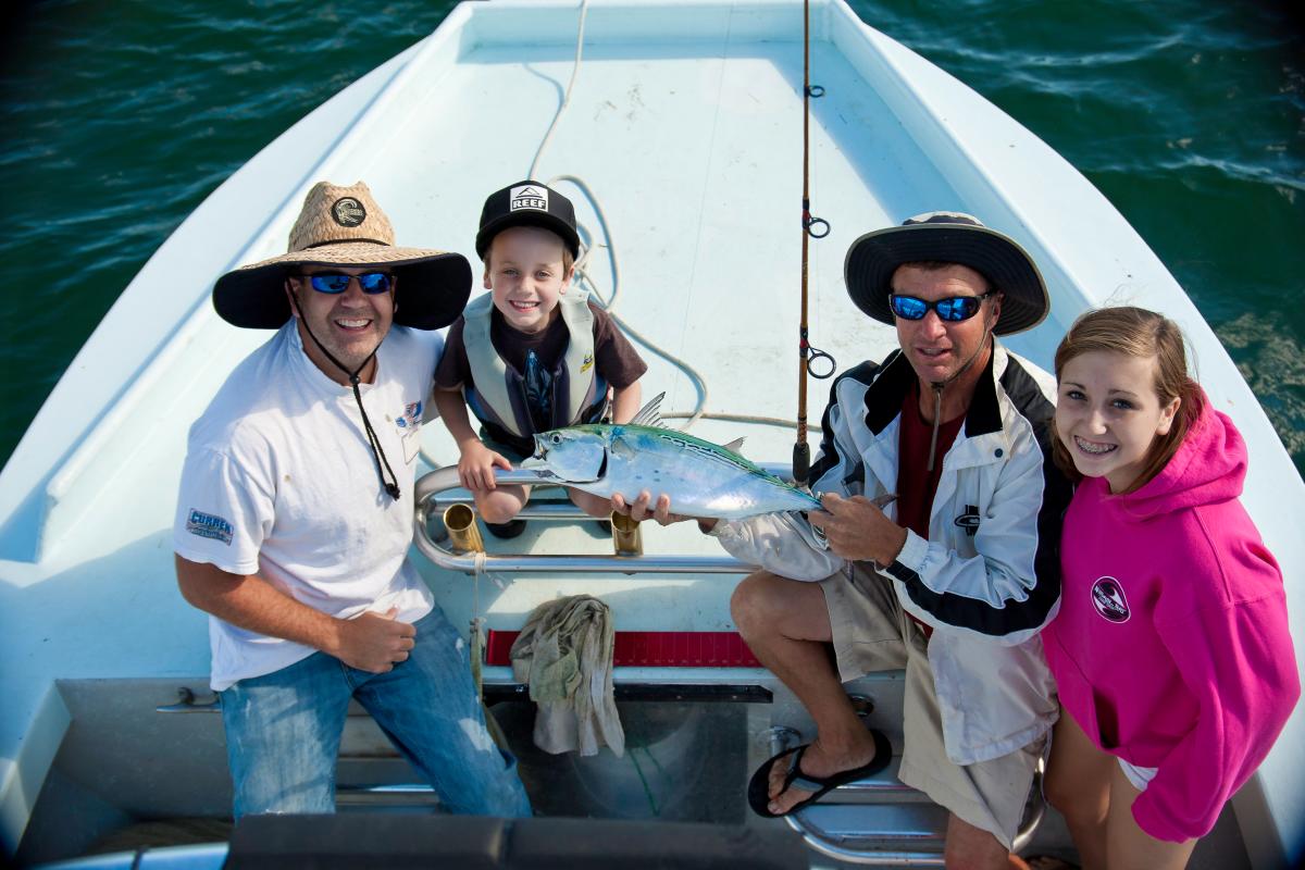 family holding fish on boat