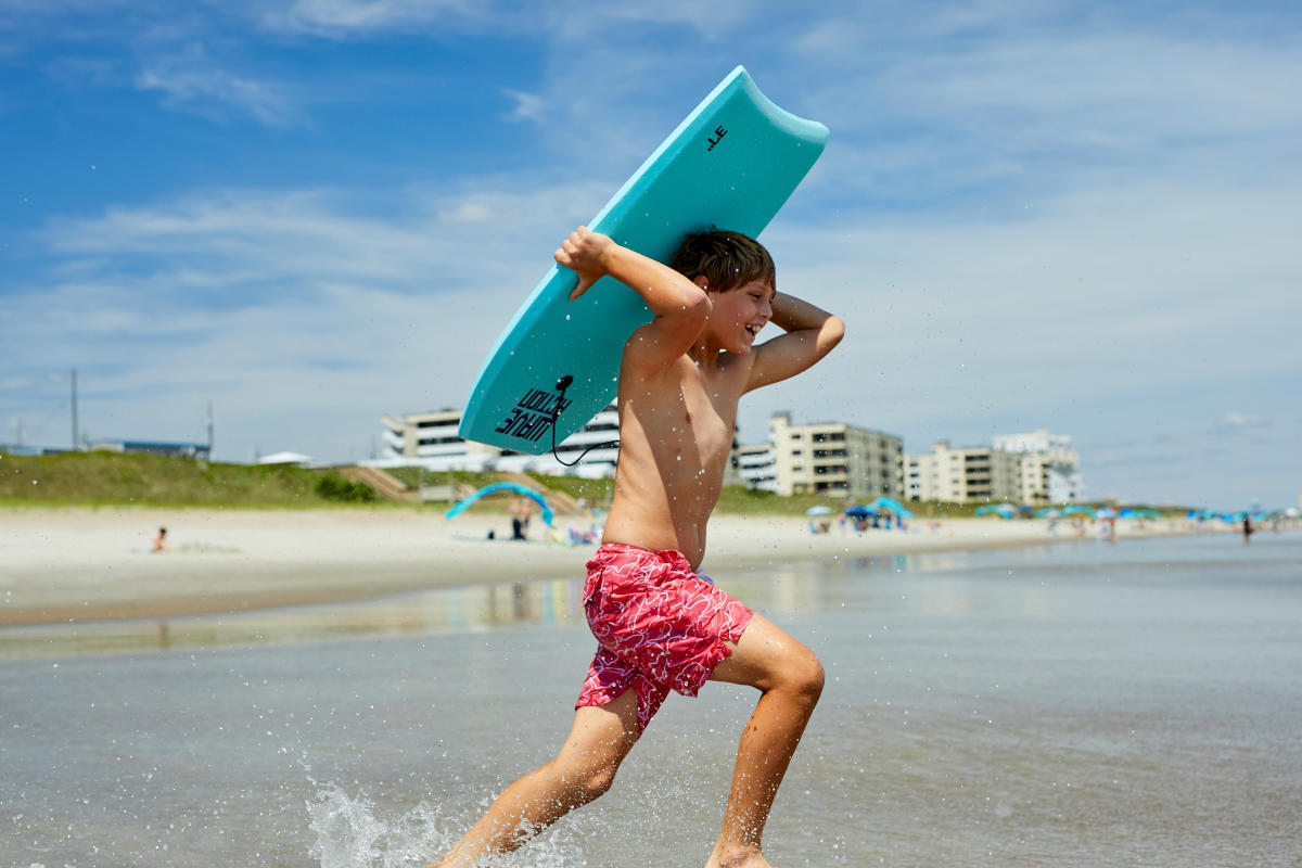 young boogie boarder running toward the ocean