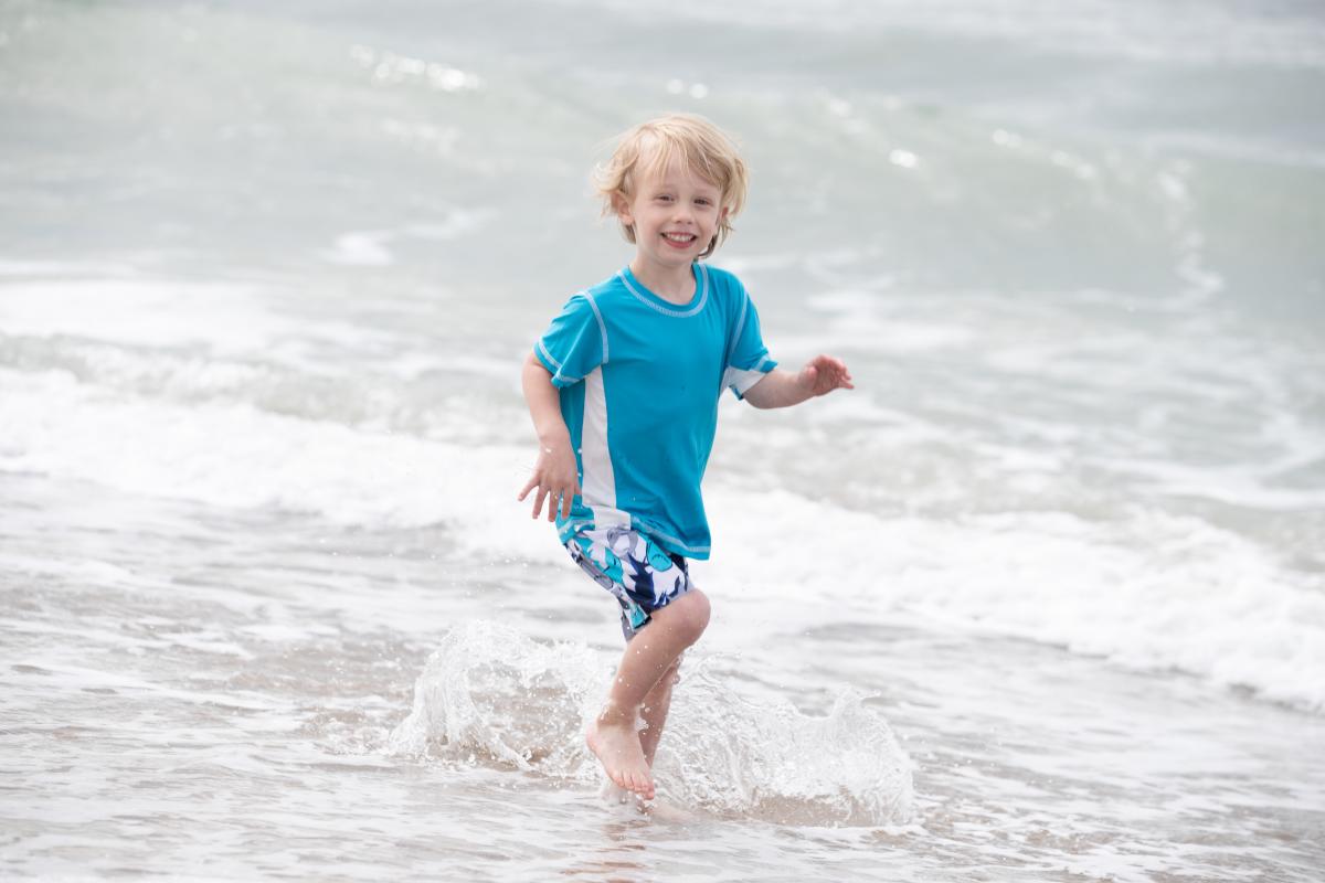 young kid wading in the surf