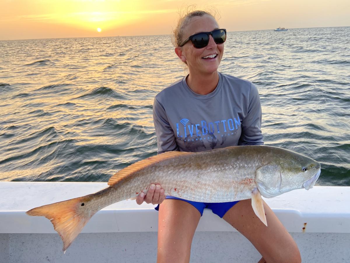 woman holding red drum with sunset in the background