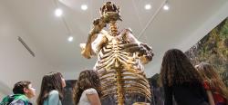The skeleton of a giant ground sloth discovered in Daytona Beach towers over children who are looking up at it.