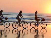 A group of female friends enjoy a sunrise bicycle ride on the beach