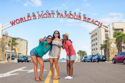 Three women post for a fun selfie under the iconic "World's Most Famous Beach" archway.