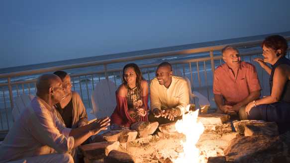 A group of friends enjoy the fire pit at an oceanfront beach bar in Daytona Beach