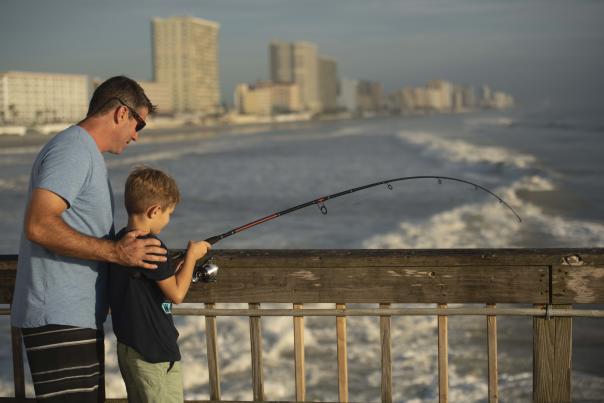 A father and son fishing on the pier over the ocean in Daytona Beach, Florida.
