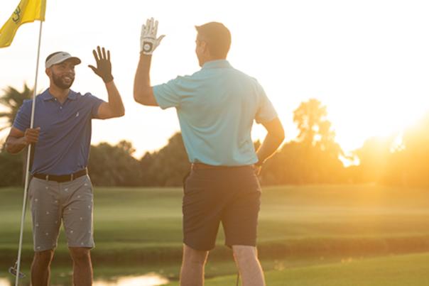 Two golfers high five each other on the green