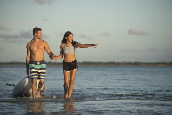 Couple strolls in the water toting a kayak