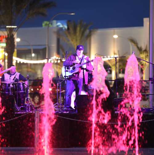 Music artists preparing to play on a stage behind a water feature at night