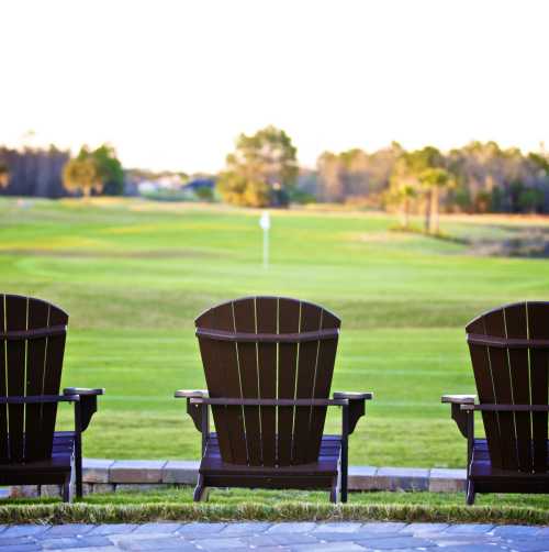 Three Adirondack chairs overlook the beautiful greens at LPGA International world-class golf course