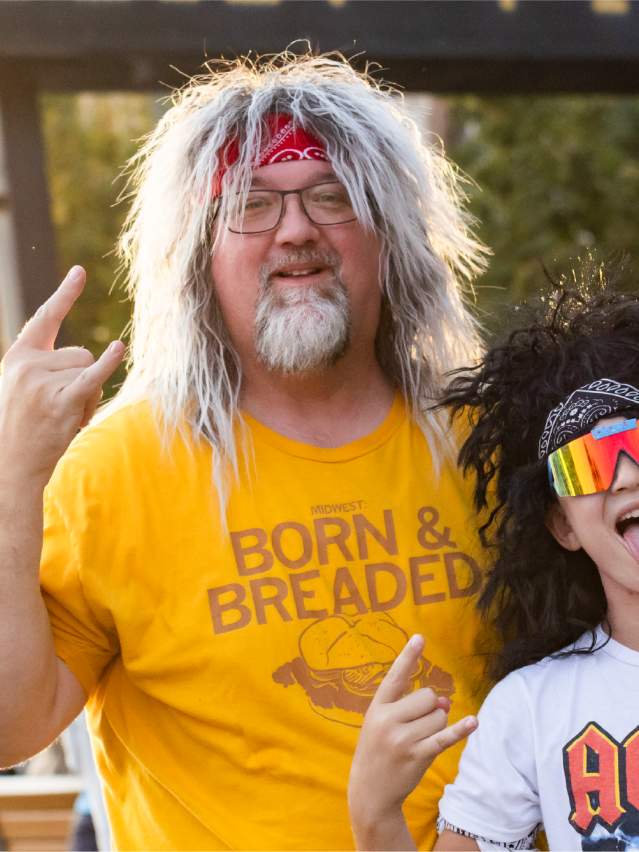 Father and Son duo with mullet wigs on sticking tongues out and using "rock-on" hand symbol.