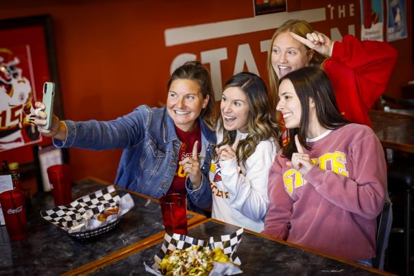 Group of four girls taking a selfie in Iowa State gear at the Station on Ingersoll