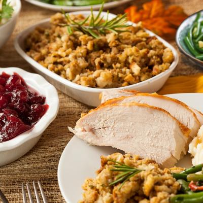 a traditional Thanksgiving dinner with cranberry sauce, stuffing, and turkey. There are also green beans and sweet potato in the background.