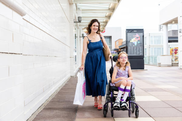 Mom walking with daughter in wheel chair at Oakbrook Center shopping destination in DuPage