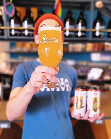 a man holding a beer in one hand and two cans of beer in the other