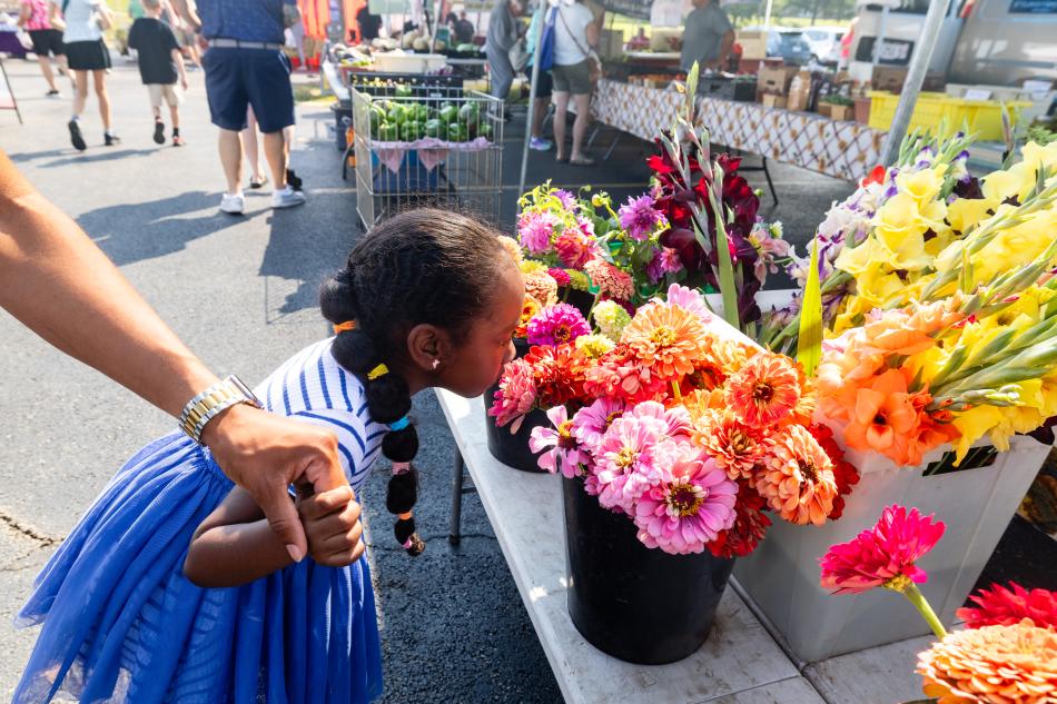 Little girl smelling flowers holding a man's hand