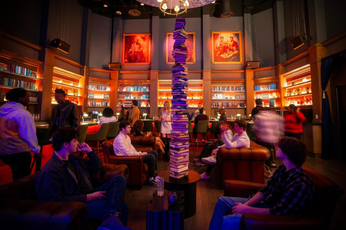 lounge of people having fun and gathering. There is a tall sculpture of books in the middle.
