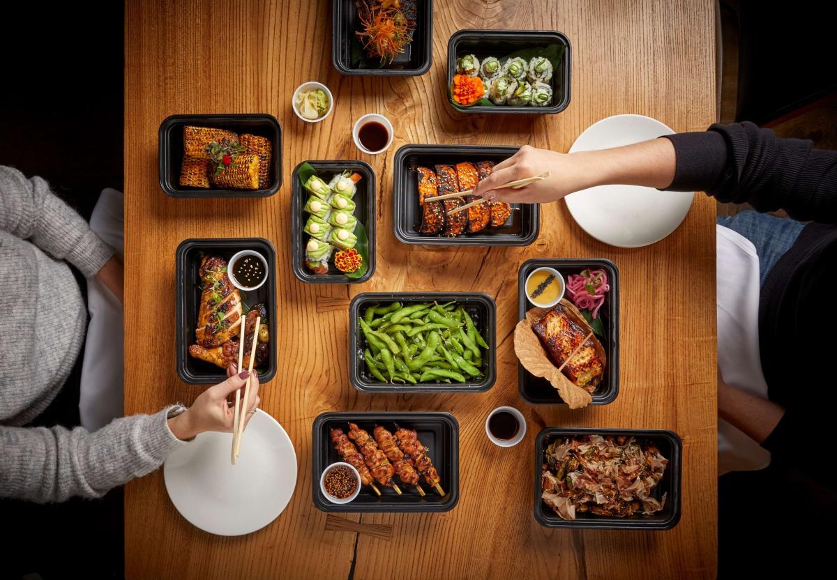 a thanksgiving dinner at Roka Akor in Oak Brook. There are two people eating with chopsticks with a variety of Asian dishes.