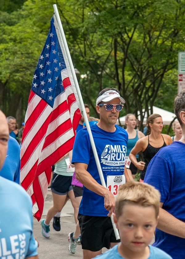 man running with a flag for a race during the Fourth of July