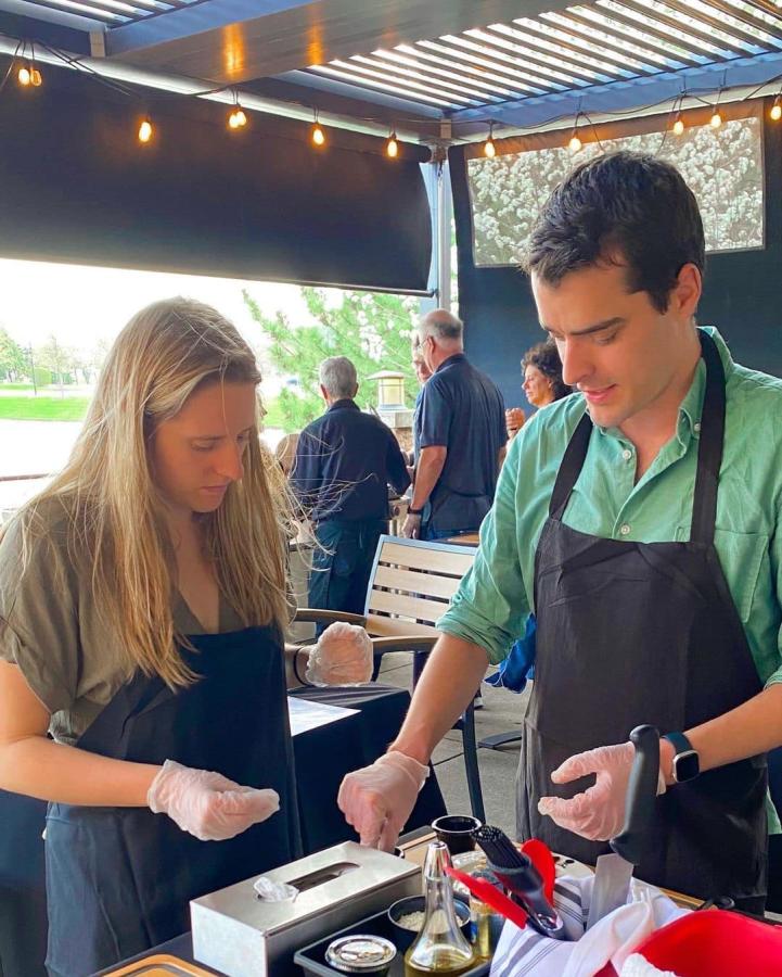 A woman with blonde hair and a man with dark hair working together during a cooking class.