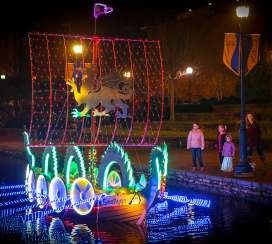 Family watching lighted boats at the Sailing Through The Winter Solstice event