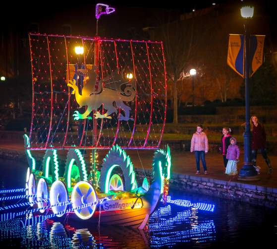 Family watching lighted boats at the Sailing Through The Winter Solstice event