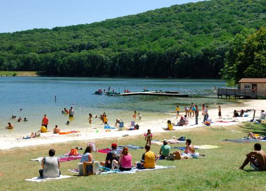 Visitors relax on the beach and enjoy swimming in the lake.