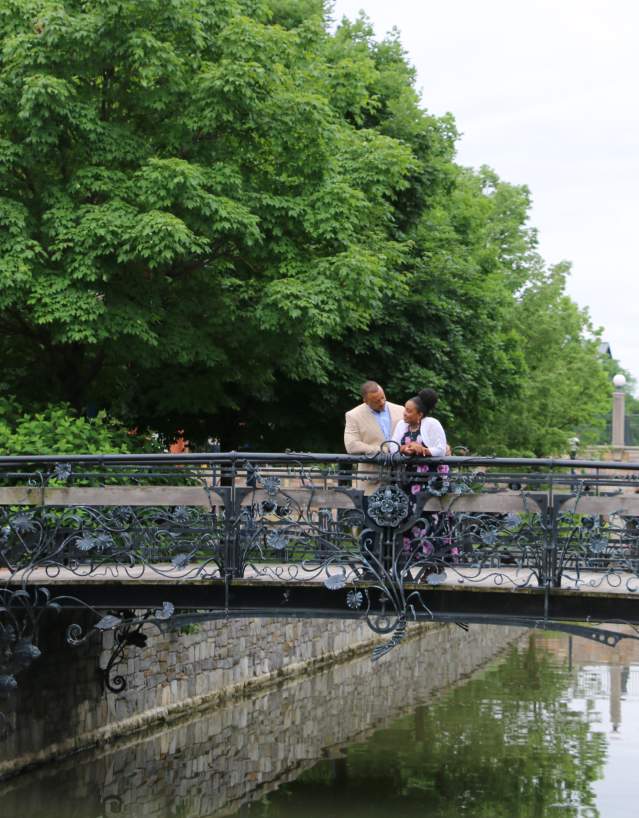 Couple standing on the Carroll Creek Park iron bridge overlooking the waterway