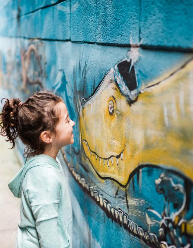 Girl smiling at dinosaur mural in Downtown Frederick