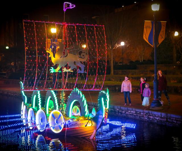 Family watching lighted boats at the Sailing Through The Winter Solstice event