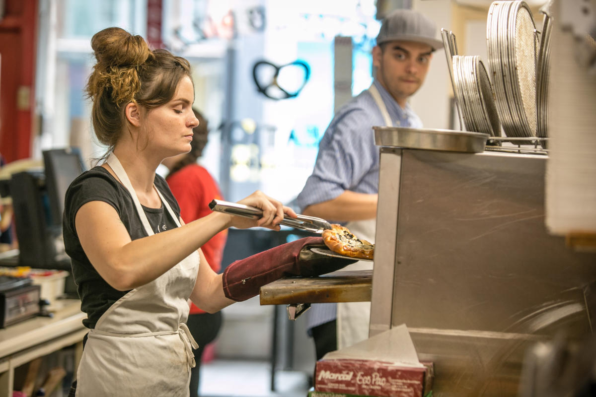 A person serving a pizza from Pretzel and Pizza