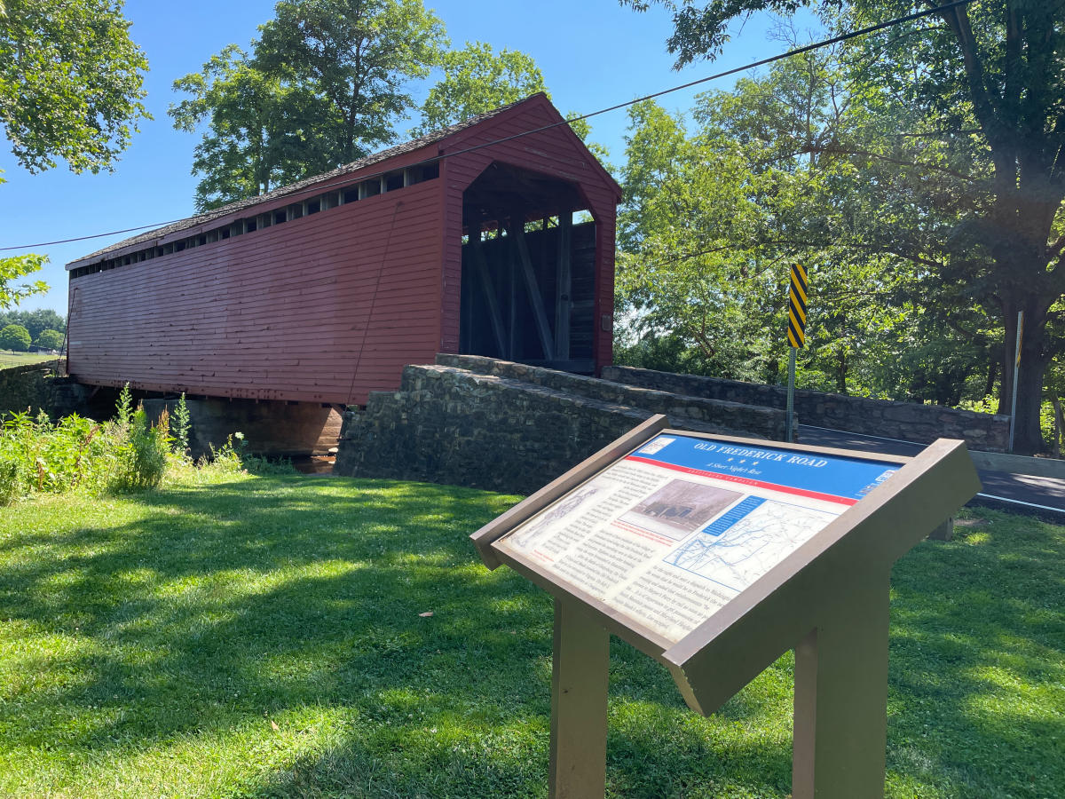 Historic Loy's Station Covered Bridge with Civil War Trails sign in front depicting the events of June 1863 as soldiers marched to the Battle of Gettysburg