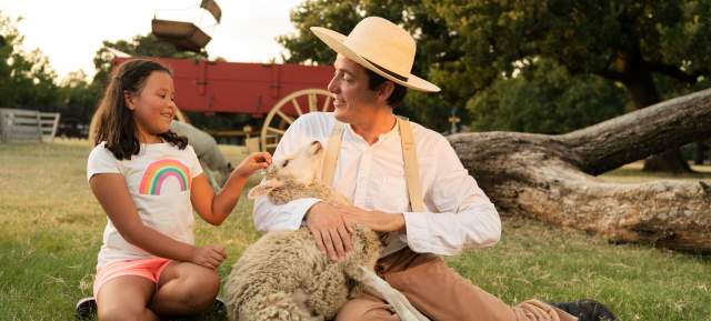 A farmhand and child with a sheep at Historic Nash Farm in Grapevine, Texas