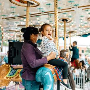 Girl riding a merry-go-round with her mother in Grapevine, Texas